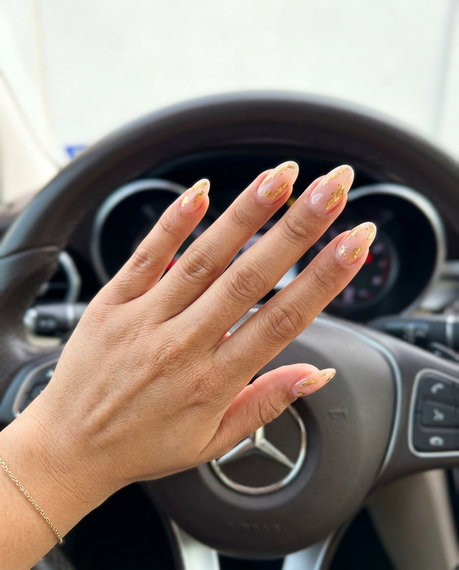 Sheer nude oval nails with metallic gold foil accents. June manicure ideas - summer trends 2026.